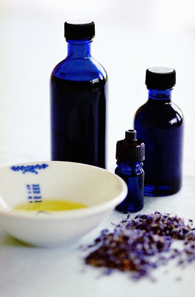 Image of blue oil bottles, a dish of oil and dried lavender used for massage