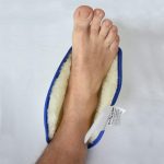 Image is a downwards photograph of a man's foot in a fleece-lined heel protector