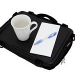 Image shows a photograph of the Trabasack Mini with a cup and pad and pen on the tray surface